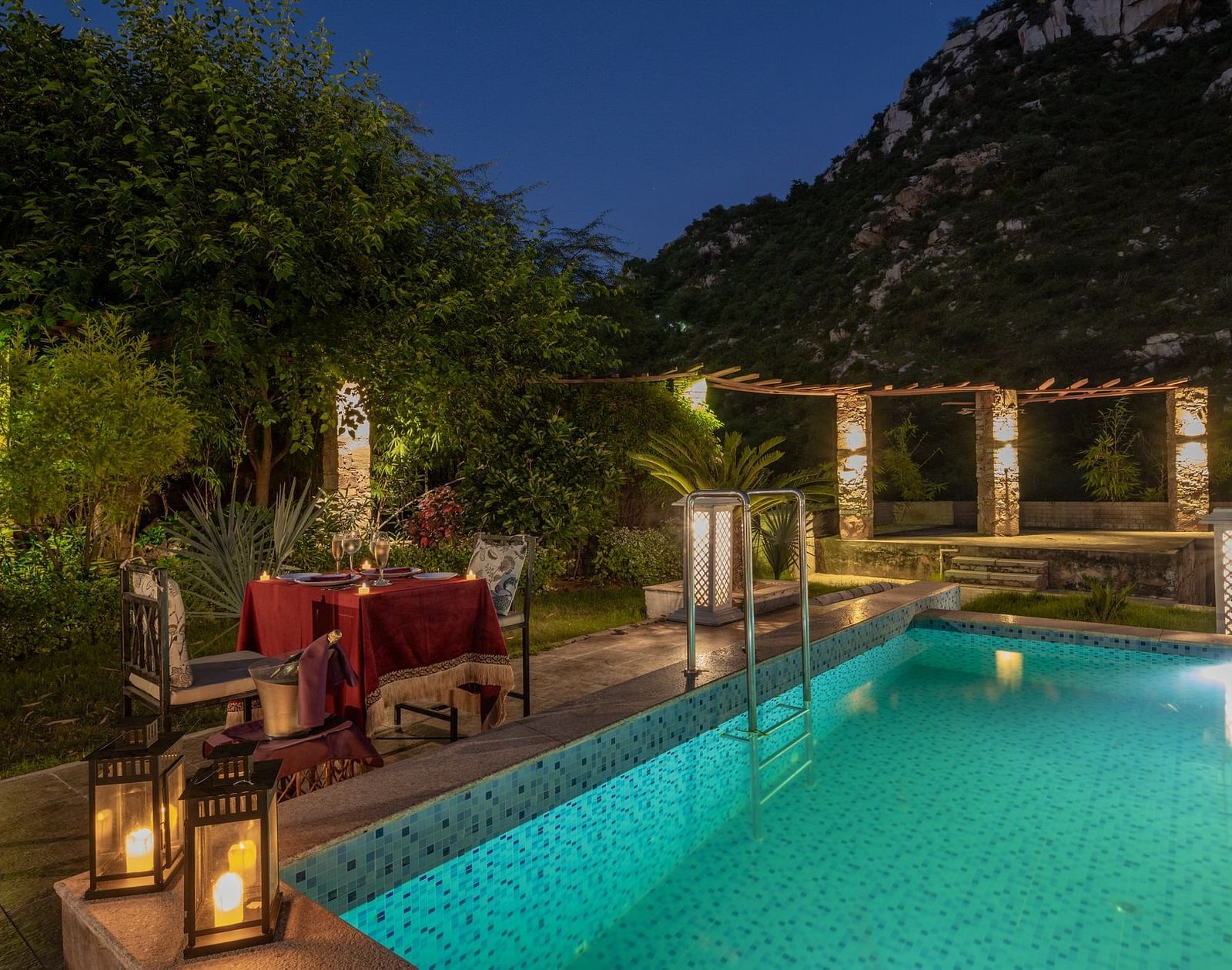 Night view of a swimming pool with a dining table and two chairs set beside it at Valley by Grassfield.
