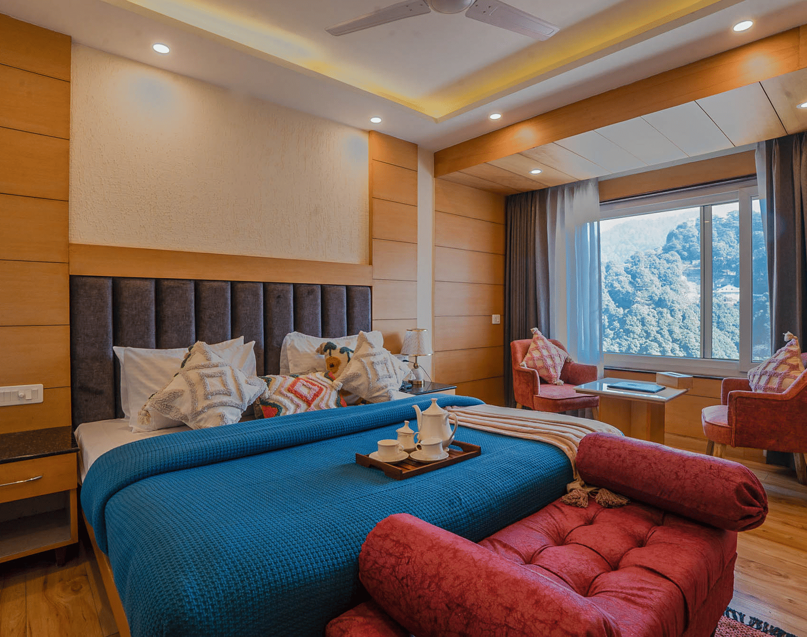 A bedroom with a bed, chairs, and large window at Perfectstayz Premium at Mall Road Hotel Super, Mussoorie.