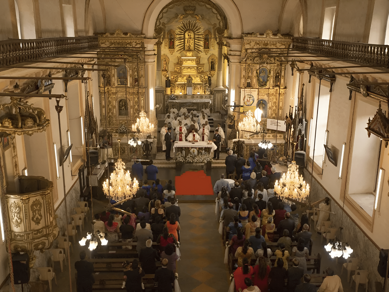 The ornate interior of a large church, with rows of pews and religious decorations.