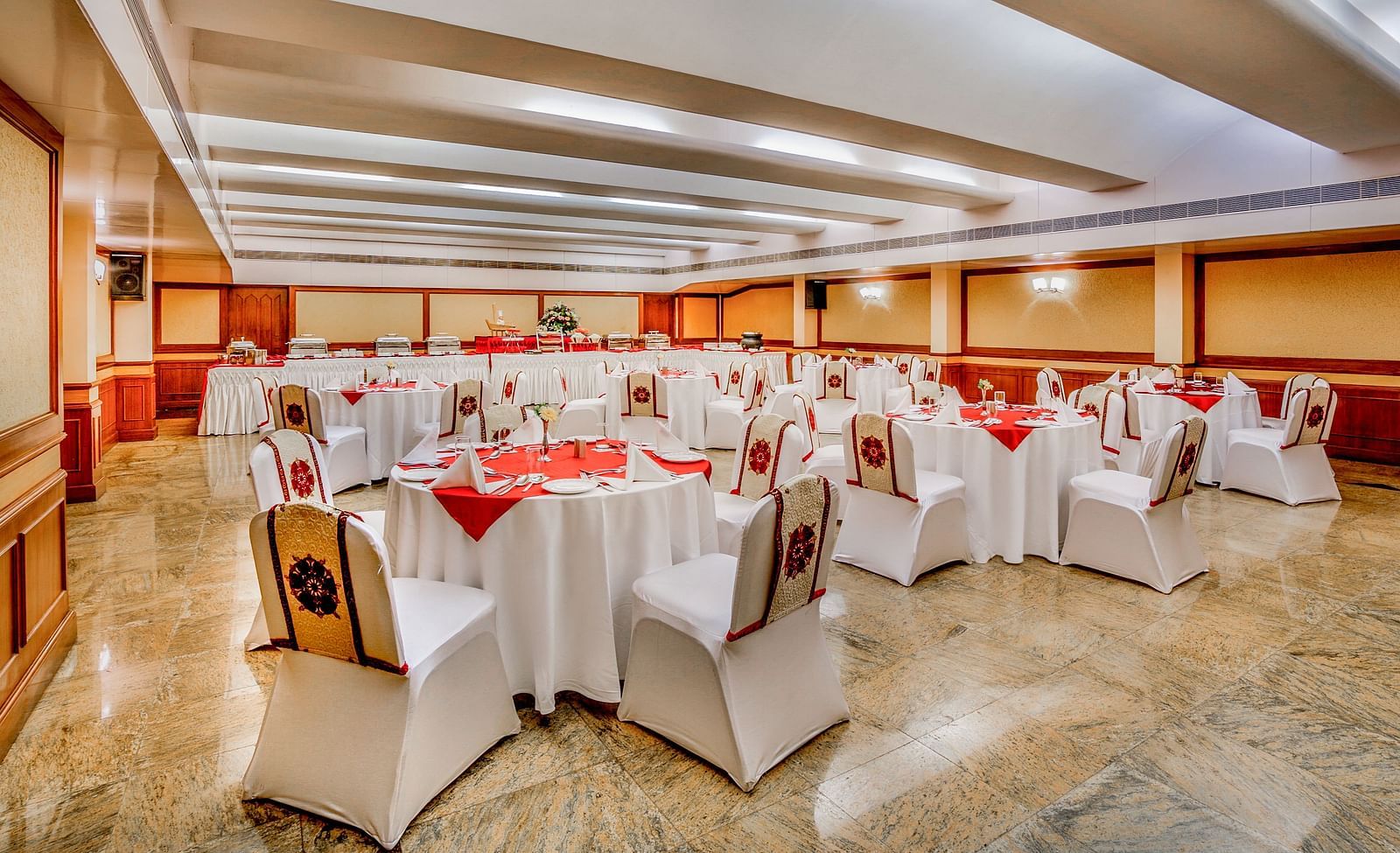 A spacious banquet hall with white-clothed tables and comfortable seating, ready for an event. - Tara, Comfort Hotel in Hyderabad - Ramoji Film City.