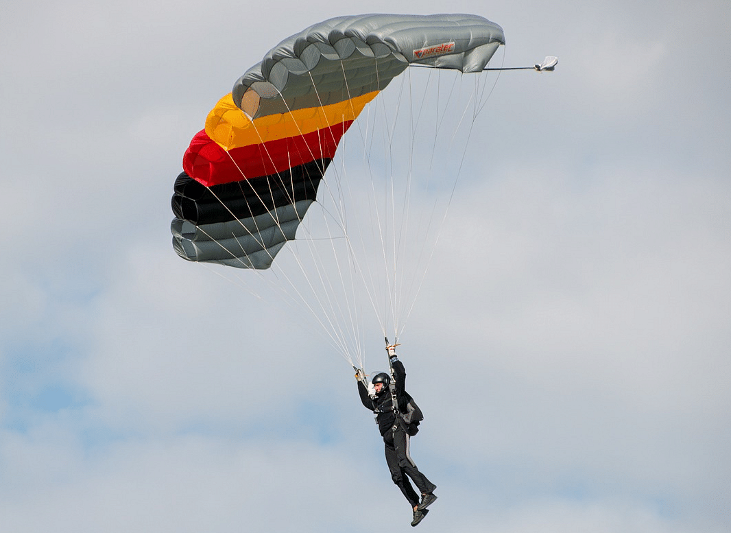 A person paragliding against a cloudy sky.