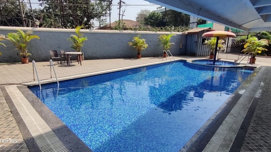 Outdoor swimming pool of Highland Resort featuring a spacious pool deck, and a children's pool canopied by an umbrella.