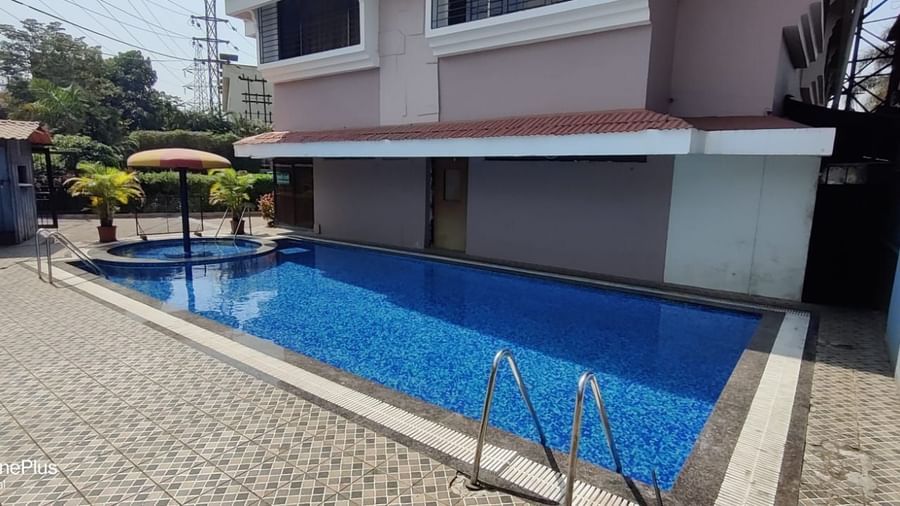 Outdoor swimming pool of Highland Resort featuring a spacious pool deck, and a children's pool canopied by an umbrella.