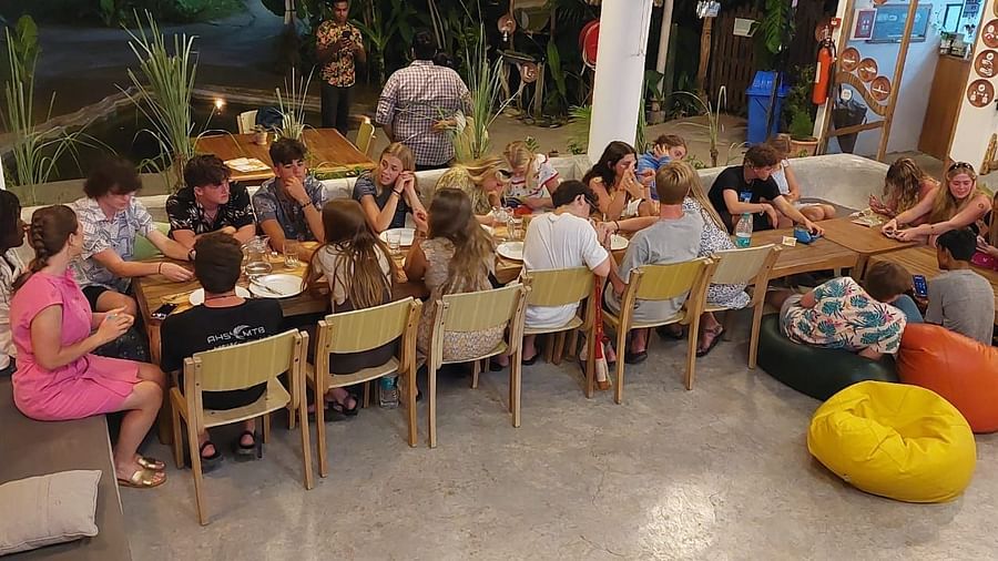 gathering of people sitting around a long dining table and seem engaged in laughter and conversation.