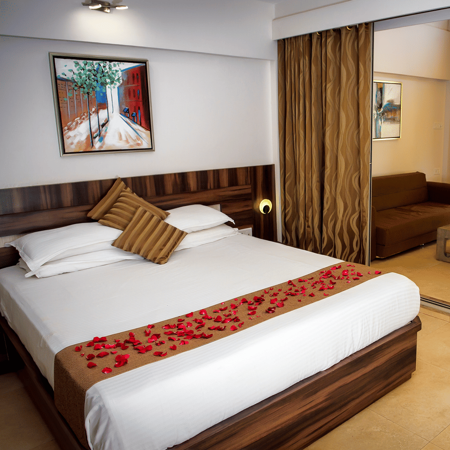 Deluxe villa bedroom interior featuring a bed, sofa and coffee table - Adamo Resort Matheran.