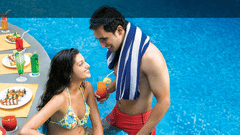 Two guests sitting poolside at the Sunken Bar in Mumbai at The Retreat Hotel and Convention Centre Madh Island, with a spread of dishes behind them.