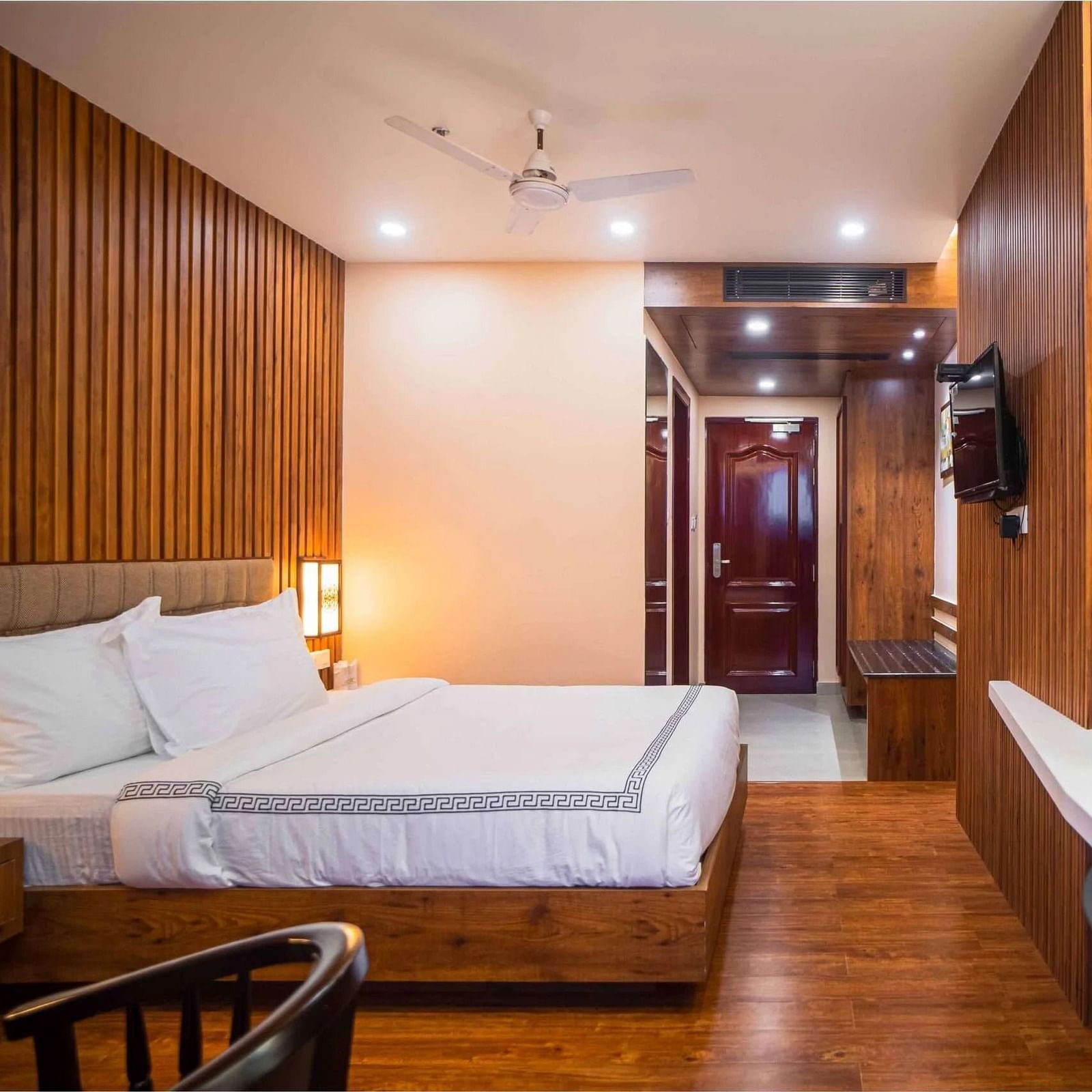 A well-furnished room at Mansha Palace offers a comfortable bed, wooden walls, a mirror, and a beverage station.
