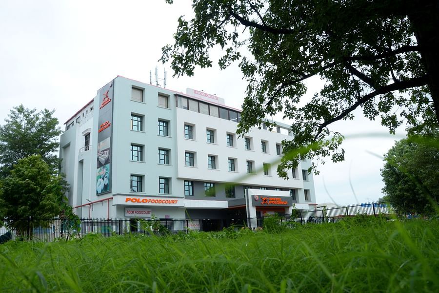 alt-text Hotel's facade  viewed from behind vibrant green foliage | Max Hotels Prayagraj