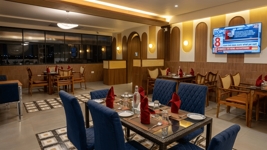Fine dining setup with neatly arranged tables, folded napkins, upholstered chairs, and ambient lighting at Kali Mirch Restaurant, Lords Riverside Resort, Muduba.