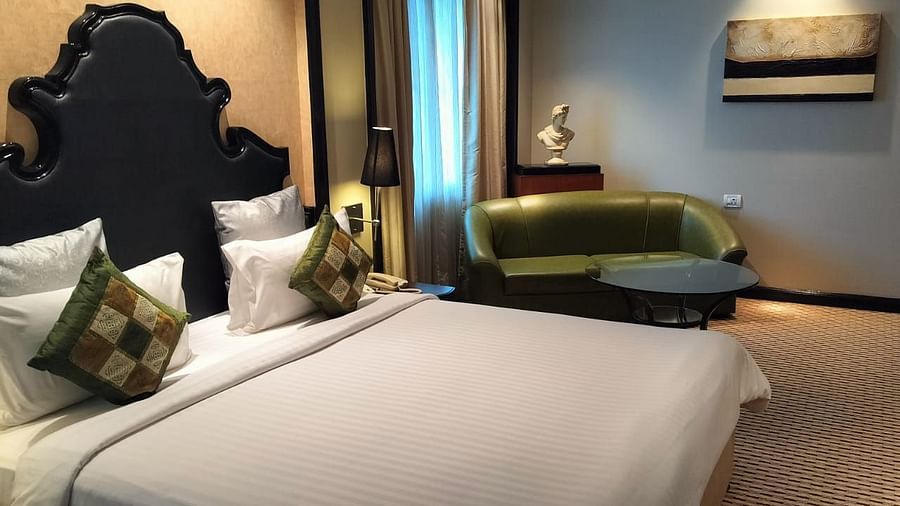 Spacious guest room featuring a large bed, lounge seating, and modern furnishings.