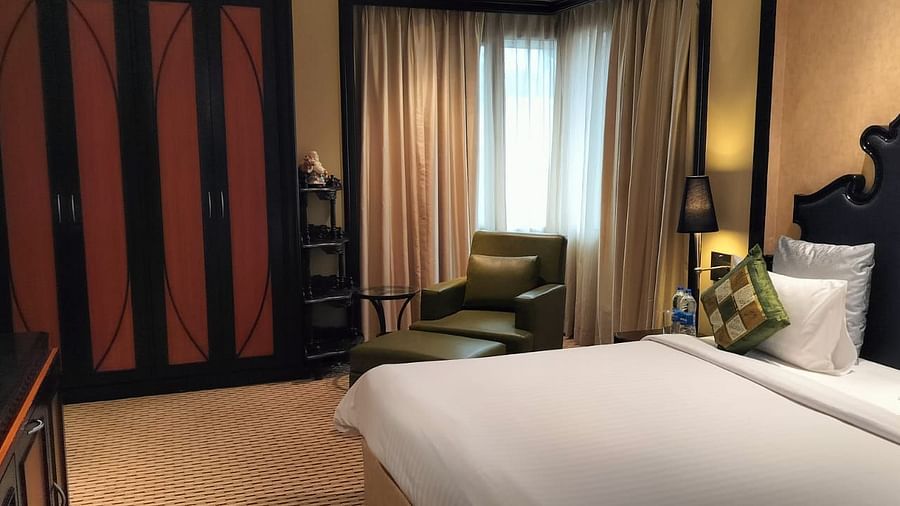 Bright guest room with large bed, window seating, and floor-to-ceiling curtains.
