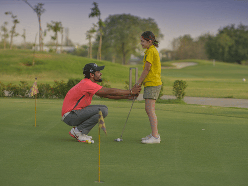 A man and a woman on the golf course with trees in the background - Karma Lakelands.