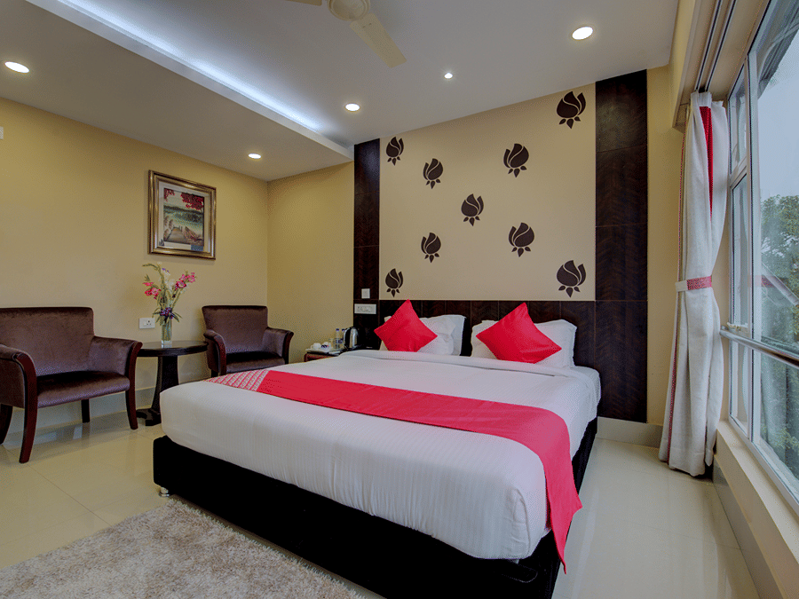 Super Deluxe Room with vibrant cushions and a table runner by the window at Central Courtyard Boutique Hotel, Siliguri