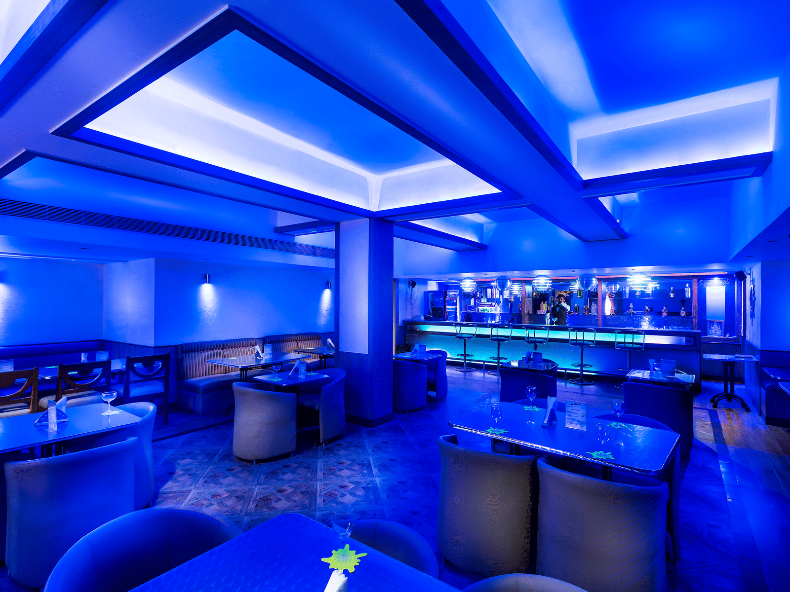 The Cellar bar in Kanchipuram featuring blue lights, cosy tables, and a bar counter - Images of Regency Kanchipuram by GRT Hotels.