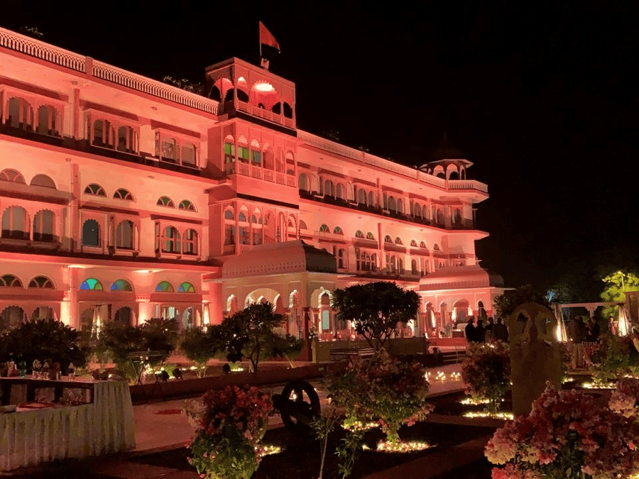 Front Facade of  Umaid Palace Dausa featuring a stretched and multi storey building lit with red light at night for an event.