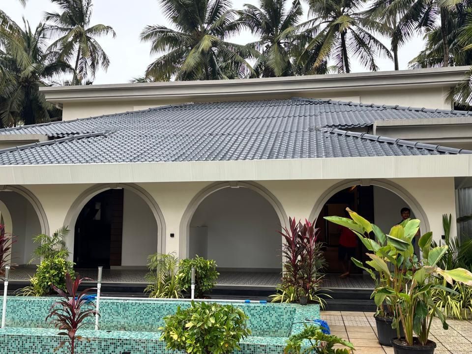 Facade view of Lamrin Morjim Goa, with arch design surrounded by trees.