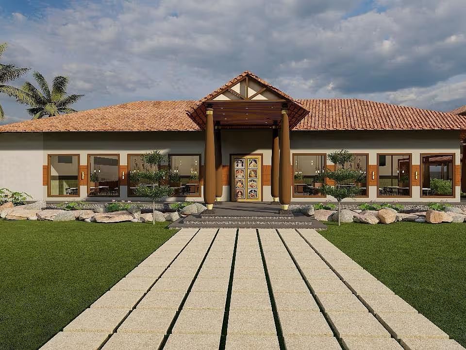 A resort building with a prominent entrance and a manicured lawn leading to it, set against a backdrop of palm trees and a cloudy sky| Ayana Resorts & Convention, Hyderabad