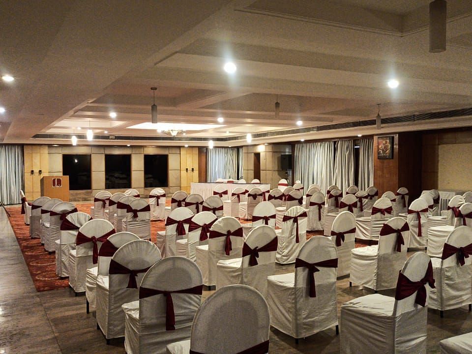 A well-lit banquet hall of Lords Plaza Ankleshwar with theatre style seating and elegant interiors creating a warm ambience