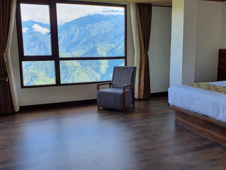 view of king size bed and chairs near the window of Premium Room at Sumitel Pelling, Geyzing