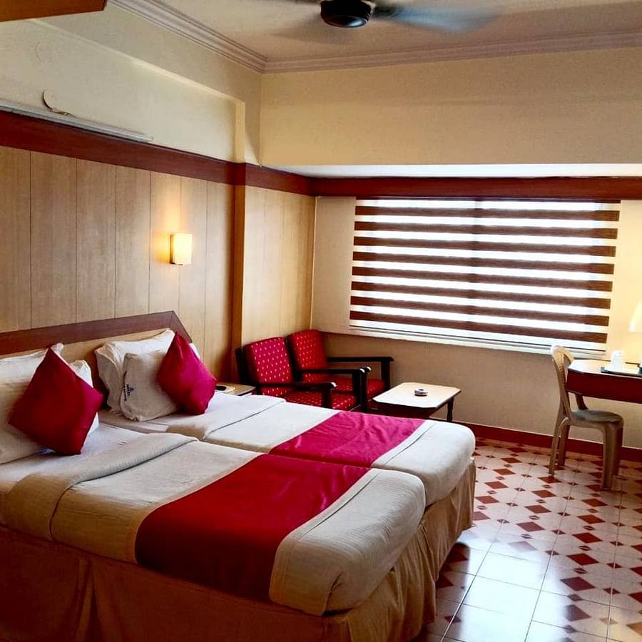Room with double bed, seating space, a work station, a mini bar, and a wall-mounted TV at Hotel Swagath, Bangalore