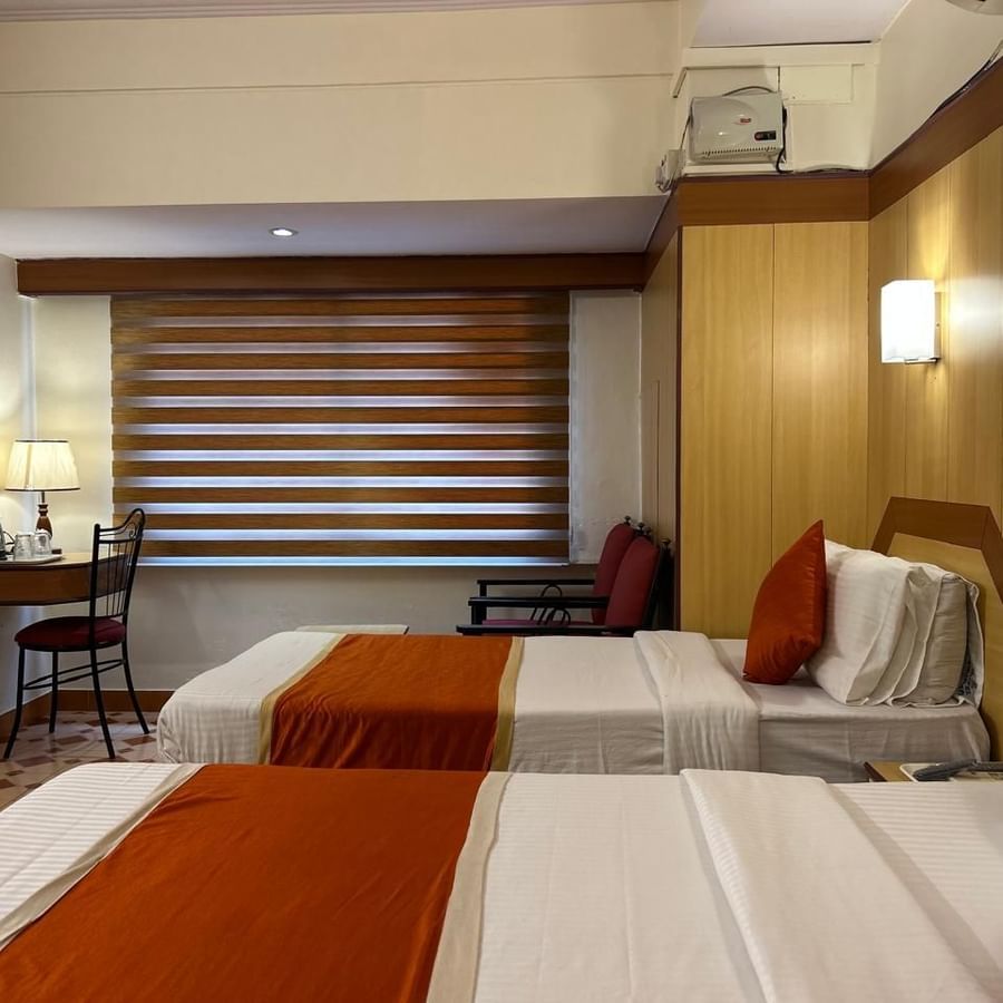 Guest room at Hotel Swagath, Bangalore with a double bed, large window blinds, and tiled flooring.