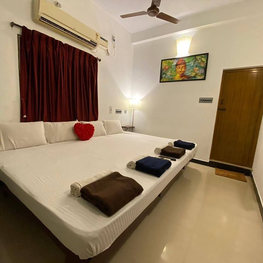 alt-text A full view of bedroom with a bed with bedding, split AC and a wall frame | La Paradise Residency, Pondicherry