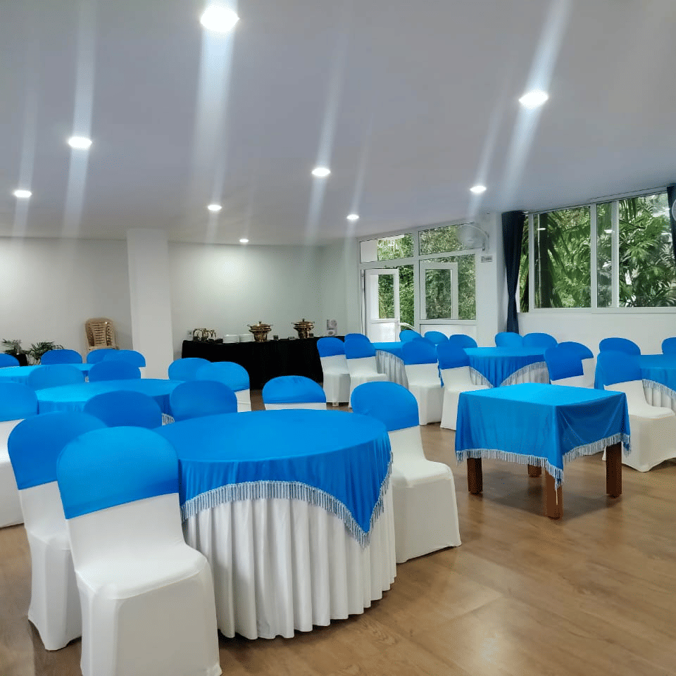 An event space set up with chairs and tables draped in white and vibrant blue covers at Coorg Orange Blossom Resort and Spa.