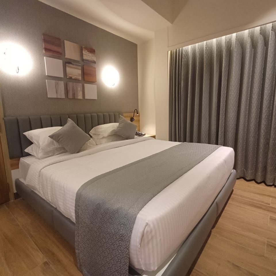 Family Suite at Hotel Paai, Hosur featuring a double size bed, a wardrobe, and a window with curtains drawn.