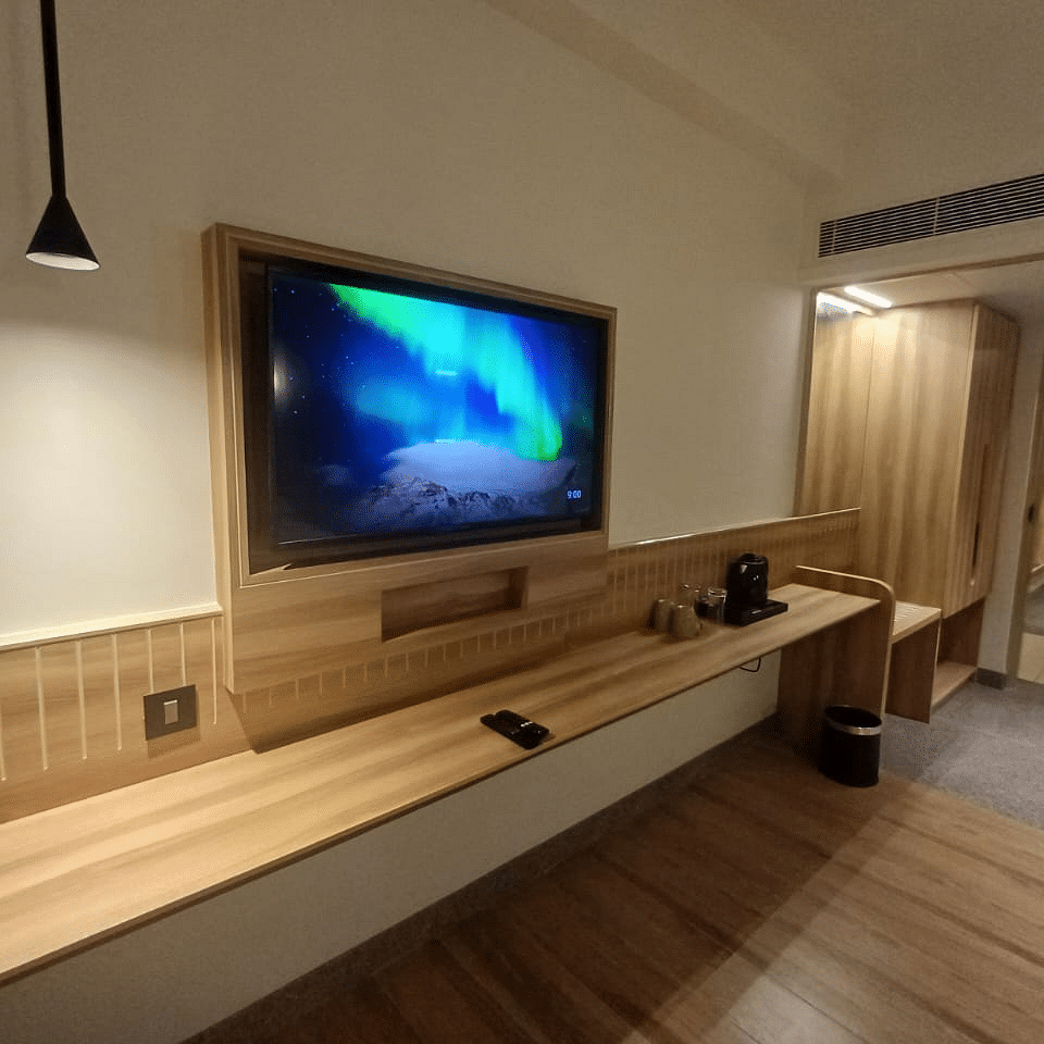 Image of a living room with television and wooden floring at Hotel Raai, Hosur.