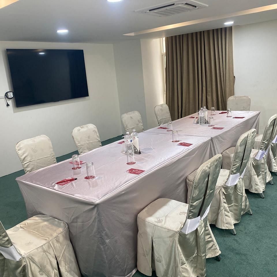 A table set for 10 with chairs, a window with curtains and TV