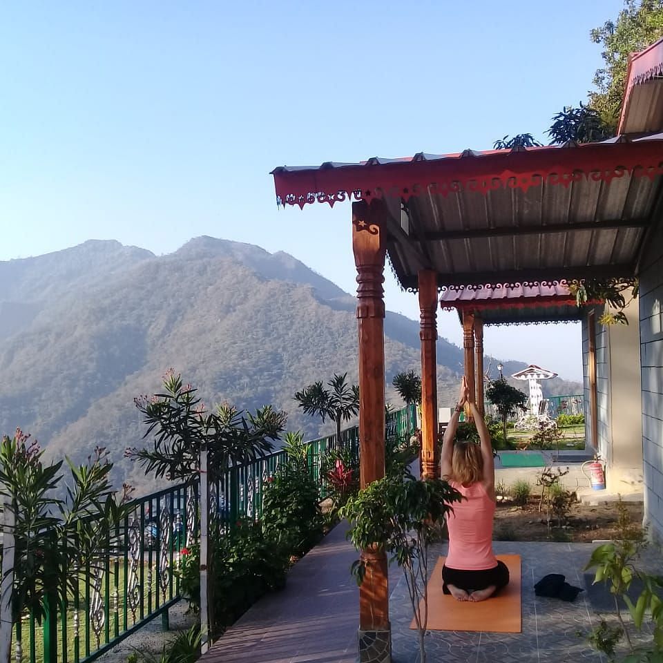 a balcony view from the room with mountains and a lady doing morning yoga