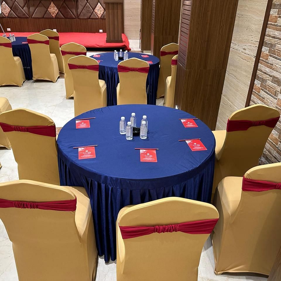 Multiple decorated round table and chairs featuring pamphlets and bottles at Shyanu Lords Eco Inn Airoli.
