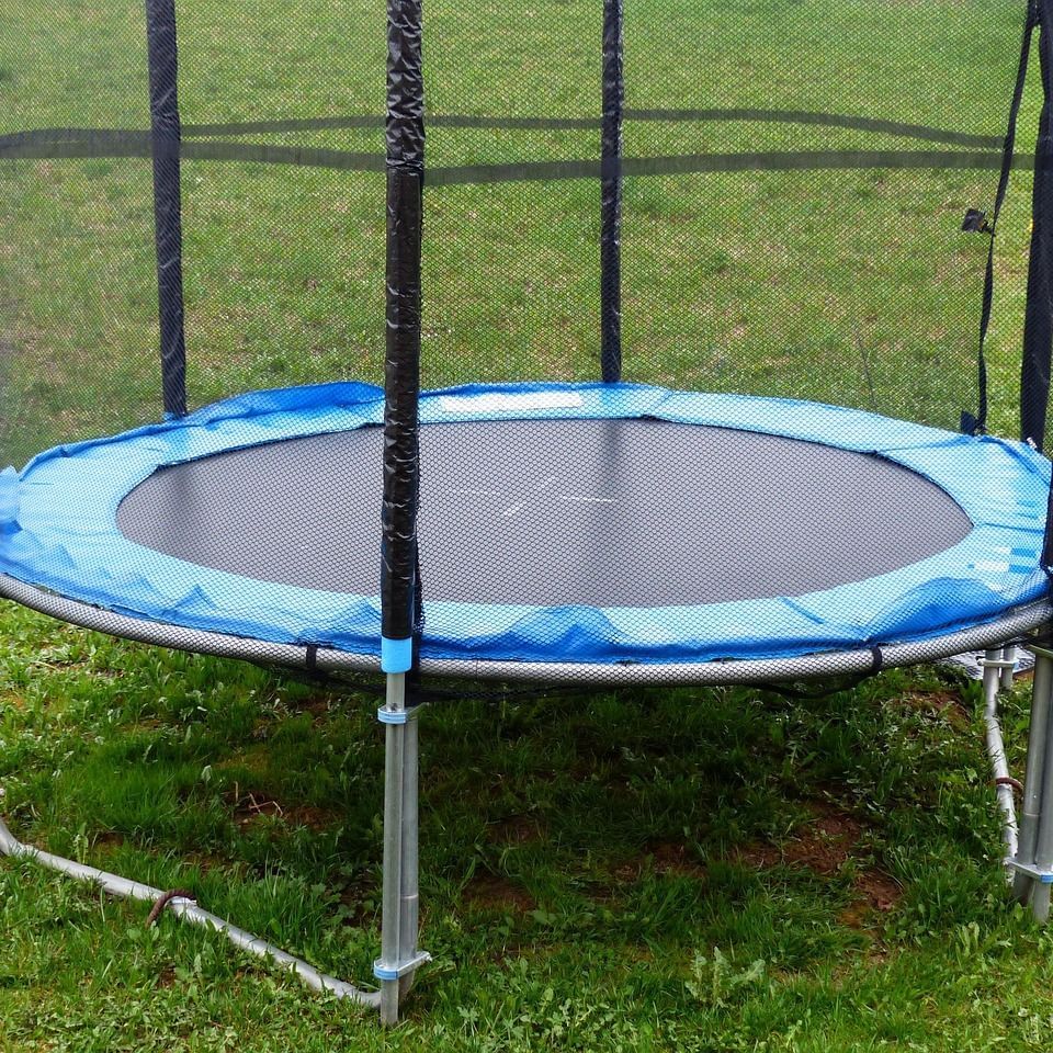 A trampoline placed on a lush green, neatly trimmed lawn.