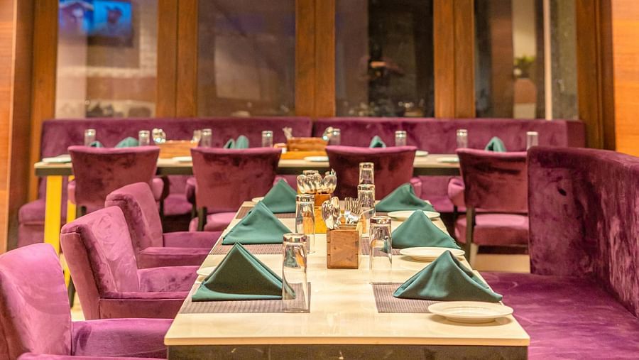 Guests at Courtyard Fine Dine, Crescent Spa & Resort, Indore, are welcomed with cushioned seating and a table elegantly arranged with a variety of culinary treats