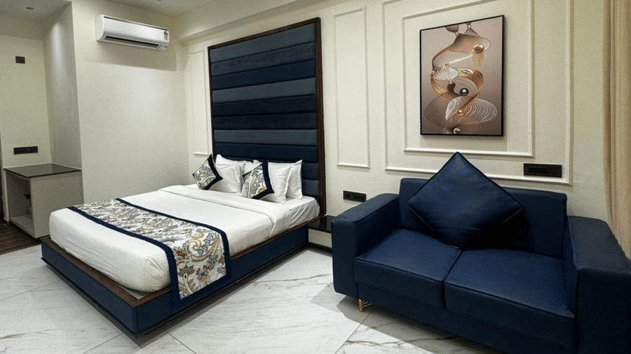 Cosy king size bed setup with nightstand and a separate seating area - Lords Swastik Studio, Kodinar