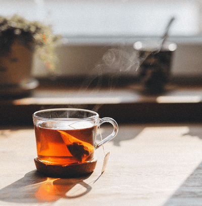 A close up shot of Darjeeling Tea placed near a window with a plant in the background. 