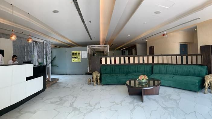 A lobby with a white reception desk, green sofas, and a decorative wall, showcasing a welcoming space - VITS Gurugram