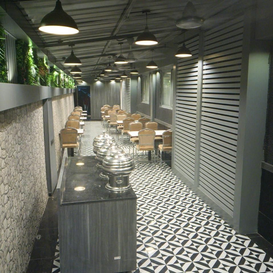 A buffet arrangement on the table set against patterned rock wall featuring a marble floor and seating space at the backdrop.