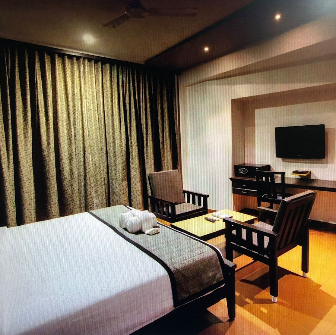 Damanganga Valley Resorts Pvt Ltd - the king size bed facing the TV and a small sitting space in the Executive Room in Daman