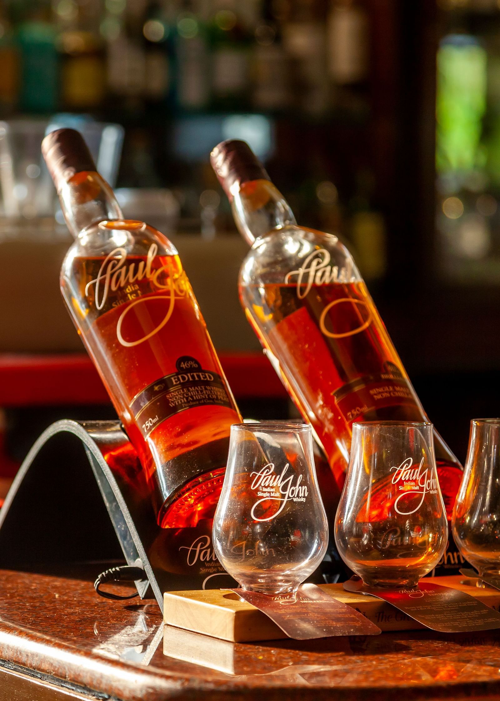 a bar counter with a two bottles kept on it and glasses next to it