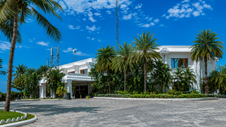 Side view of Chariot Beach Resort showcasing its elegant white architecture, palm trees, and beautifully landscaped garden pathways.