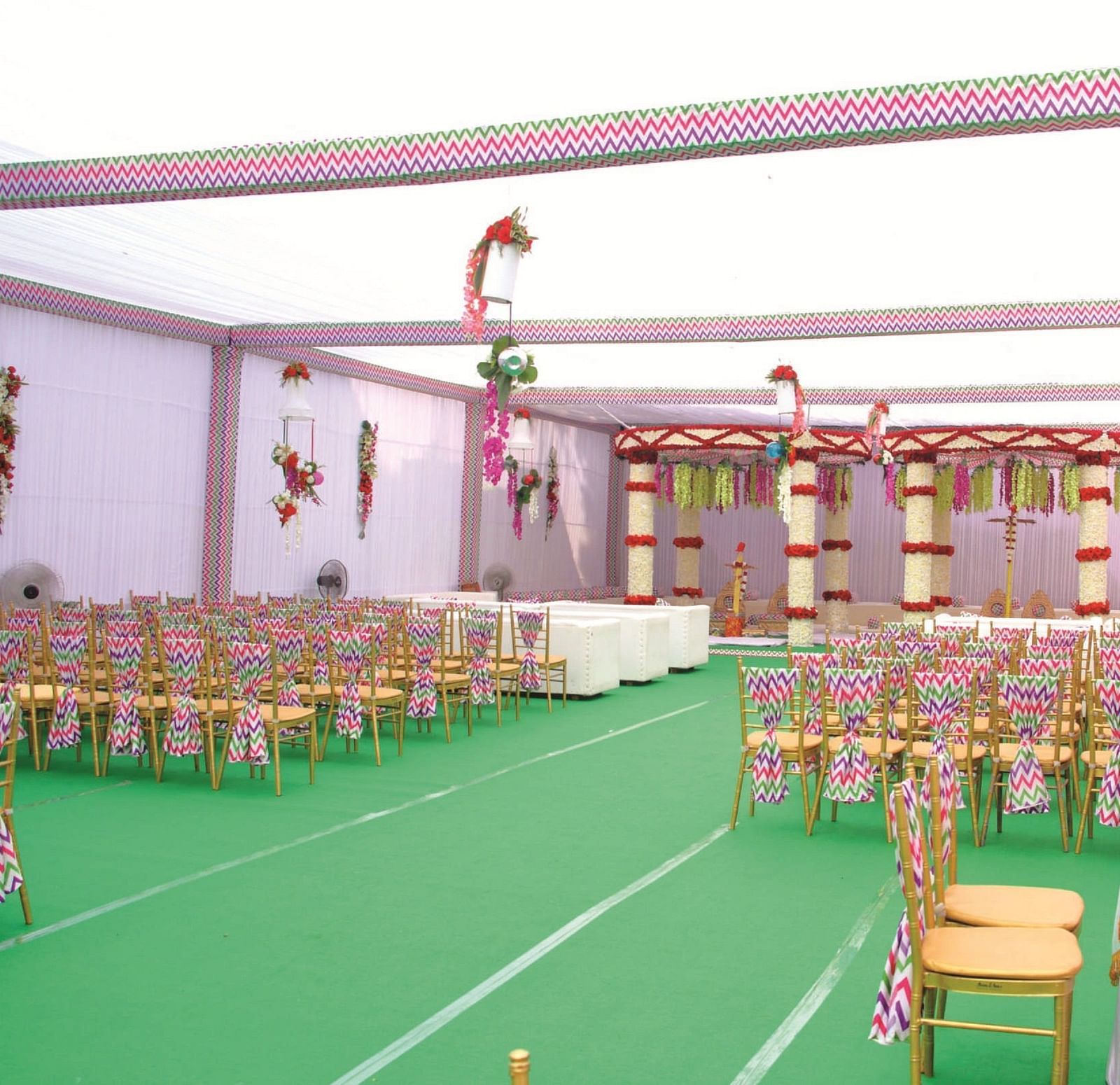 A full view of a banquet hall with green carpet and floral arrangements for an event | Gemini Continental
