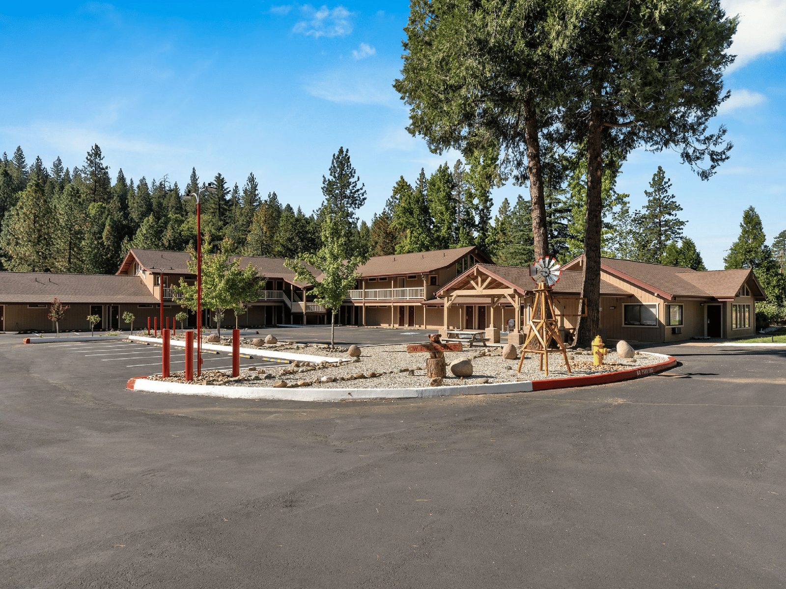 A wide view of the exterior of a hotel with green foliage in the background.