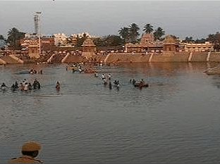Panoramic view of Kumbakonam, a serene water body with temple structures on the banks, offering a glimpse of Dharasuram’s heritage