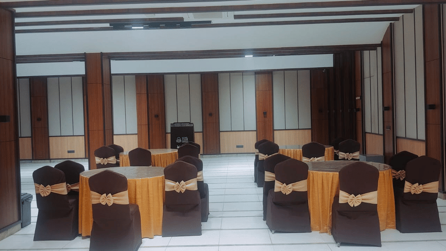 Elegant private party room with round banquet tables, chair covers, and modern wooden interiors, ideal for celebrations, meetings, and corporate events.