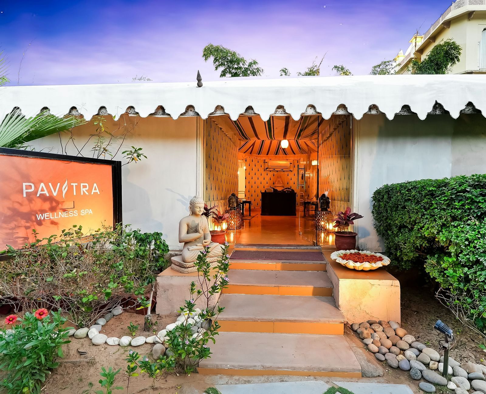 Entrance to a tent with potted plants on either side and twilight sky above - Rajasthali Resort & Spa, Jaipur.