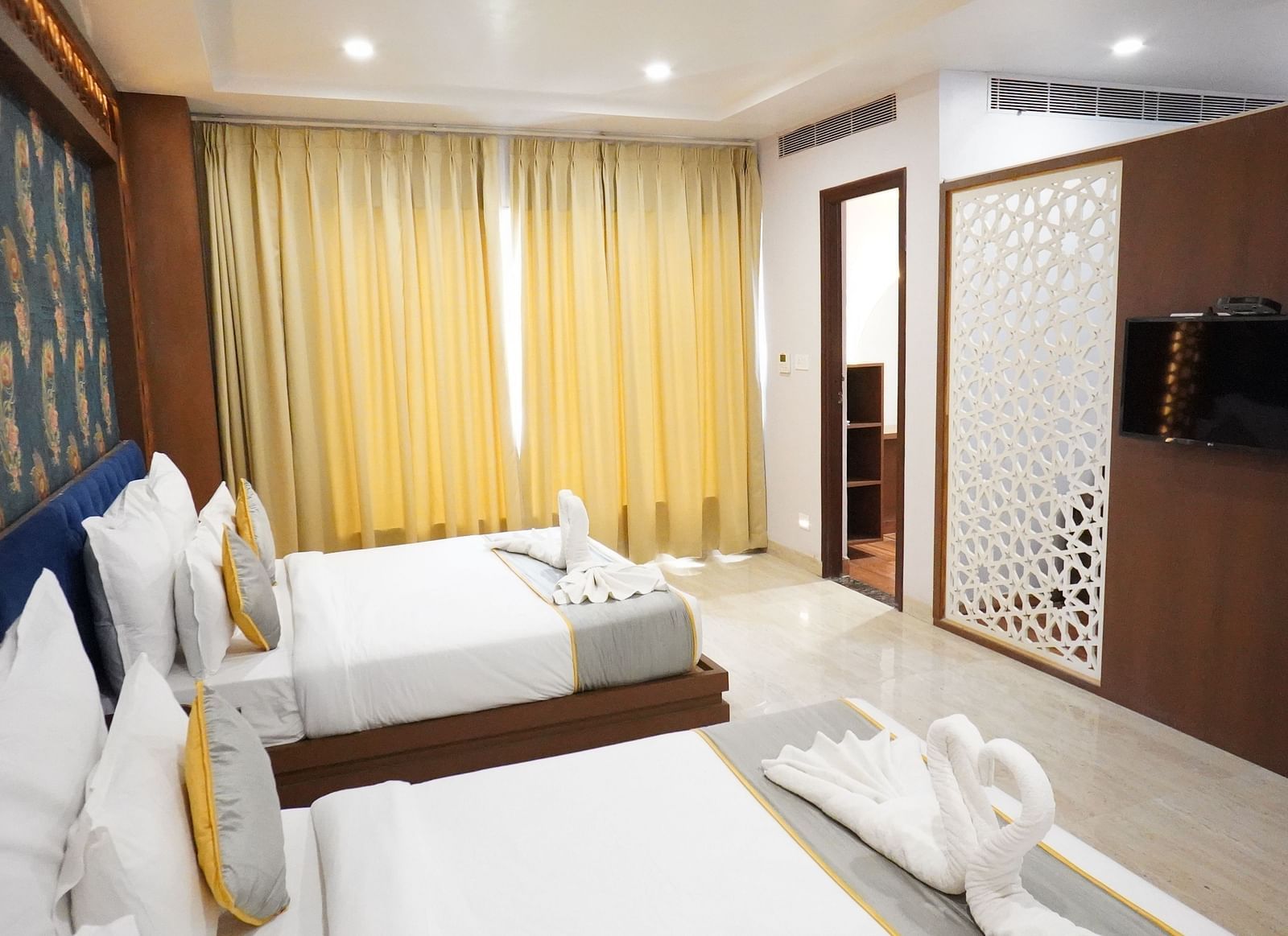 An interior shot of a bedroom at the Bamboo Saa Mulberry Resort  with two twin beds with white linens and decorative throws are neatly made.