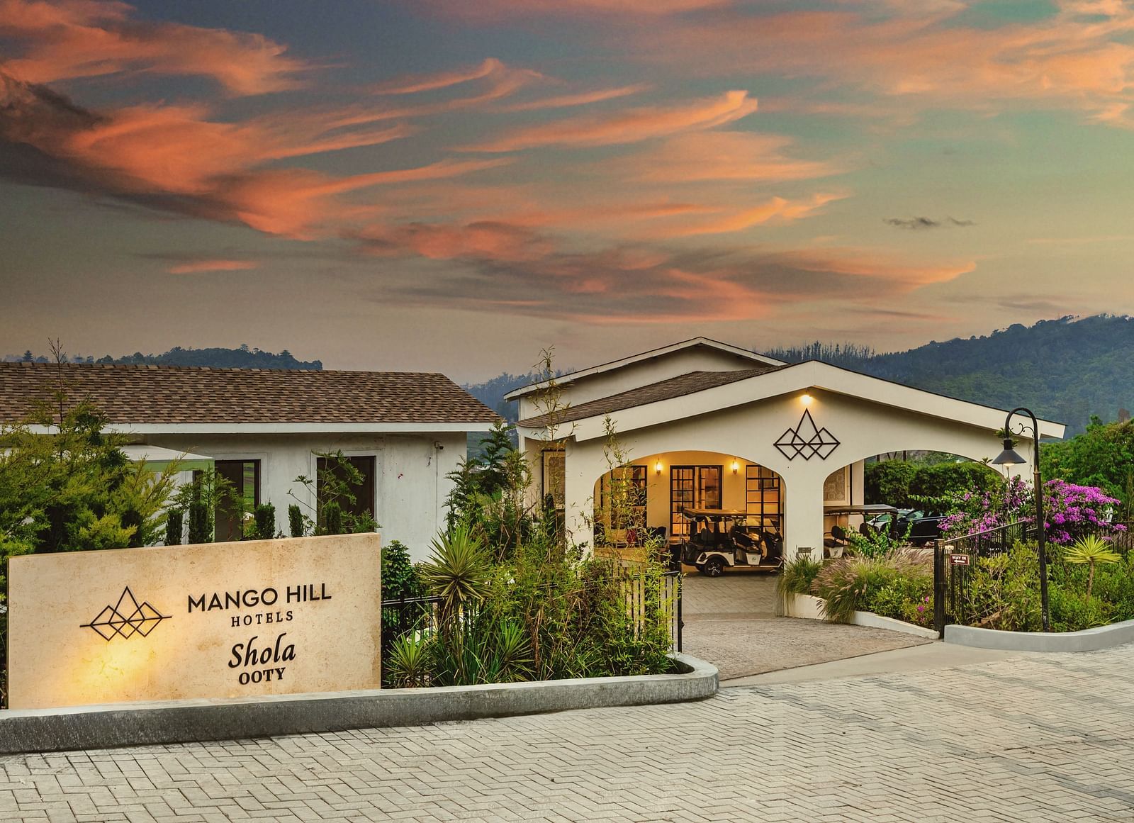 Panoramic view of Mango Hill Shola, Ooty, nestled within tea plantations and hills, blending into the expansive surrounding landscape.