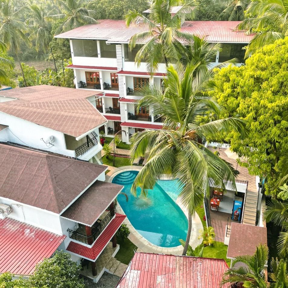 An aerial view of the The Verda de Miranda Resort nestled amidst palm trees, featuring multiple buildings and a turquoise pool.