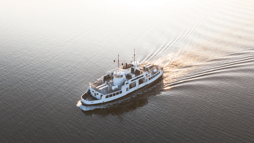 An aerial view of a ferry travelling on a water body while leaving waves behind - How to Reach Havelock Island